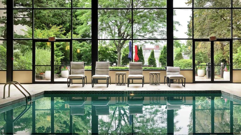 an indoor pool with lounge seating and a view of trees