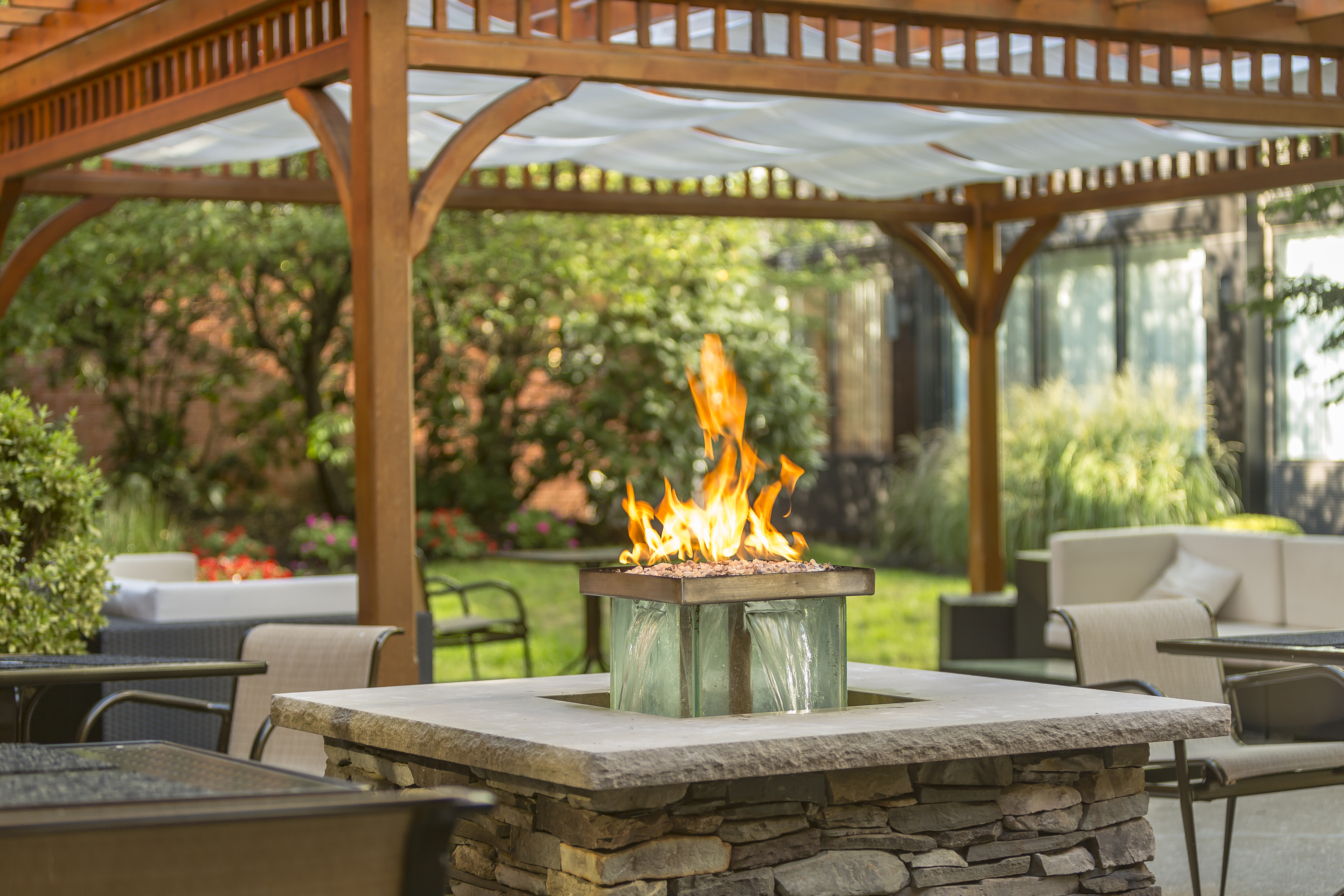 Tables and Chairs Under Pavilion Around Fire Pit on Hotel Exterior Patio