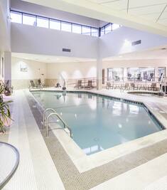 Tables and Chairs Around Indoor Pool and Whirlpool With Skylight and View Into Fitness Center