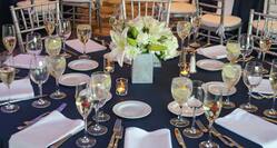 Place Settings, Flowers, Candles on Round Table With Blue Linens Set Up For a Wedding Reception