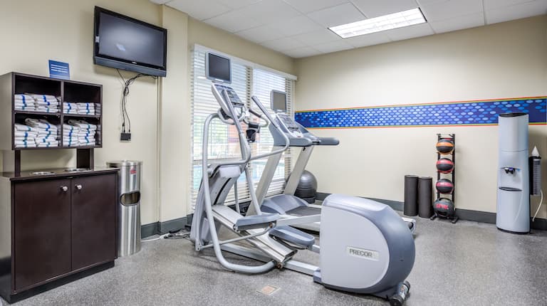 Fitness Center with Exercise Equipment, Towels and a Wall Mounted TV
