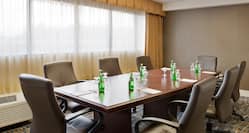 LArge Window With Sheer Drapes, and Seating For 8 Around Large Wood Table in Executive Boardroom  