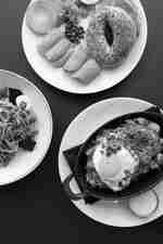 Platos para el desayuno que incluyen huevos, verduras de hojas verdes y platos principales preparados sobre una mesa de comedor.