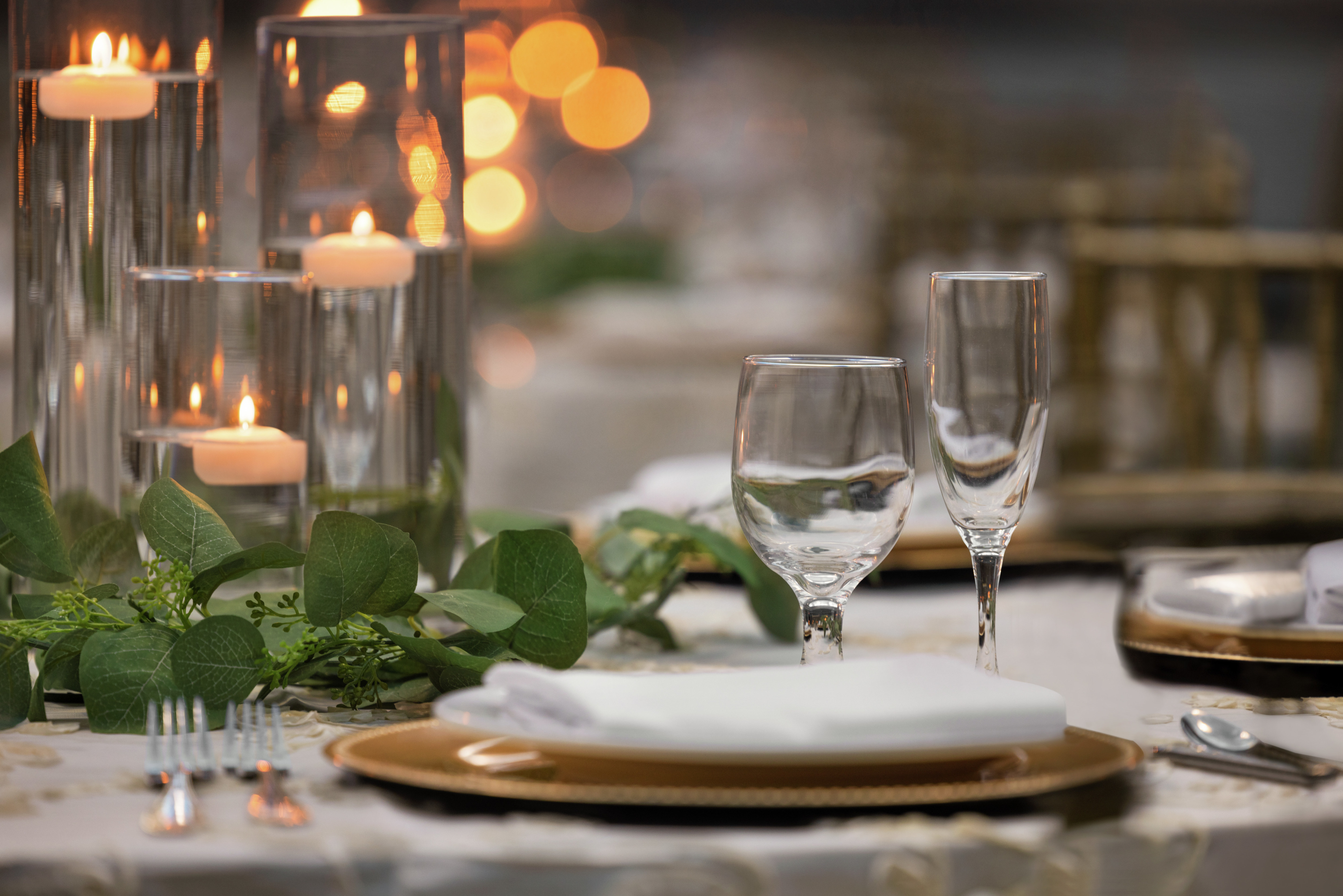 Beautiful detail of banquet table setup featuring candles and greenery.