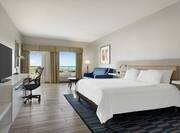 Spacious guest room featuring comfortable king bed, sofa, and stunning outside view.