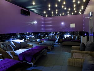 Dimly Lit Relaxation Room With Purple Walls, Large Lounge Seating, and Armchairs