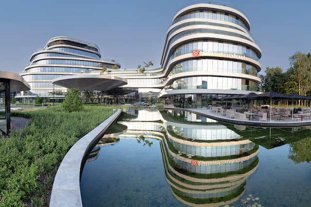 Modern hotel exterior with curved architecture, reflecting off pond.