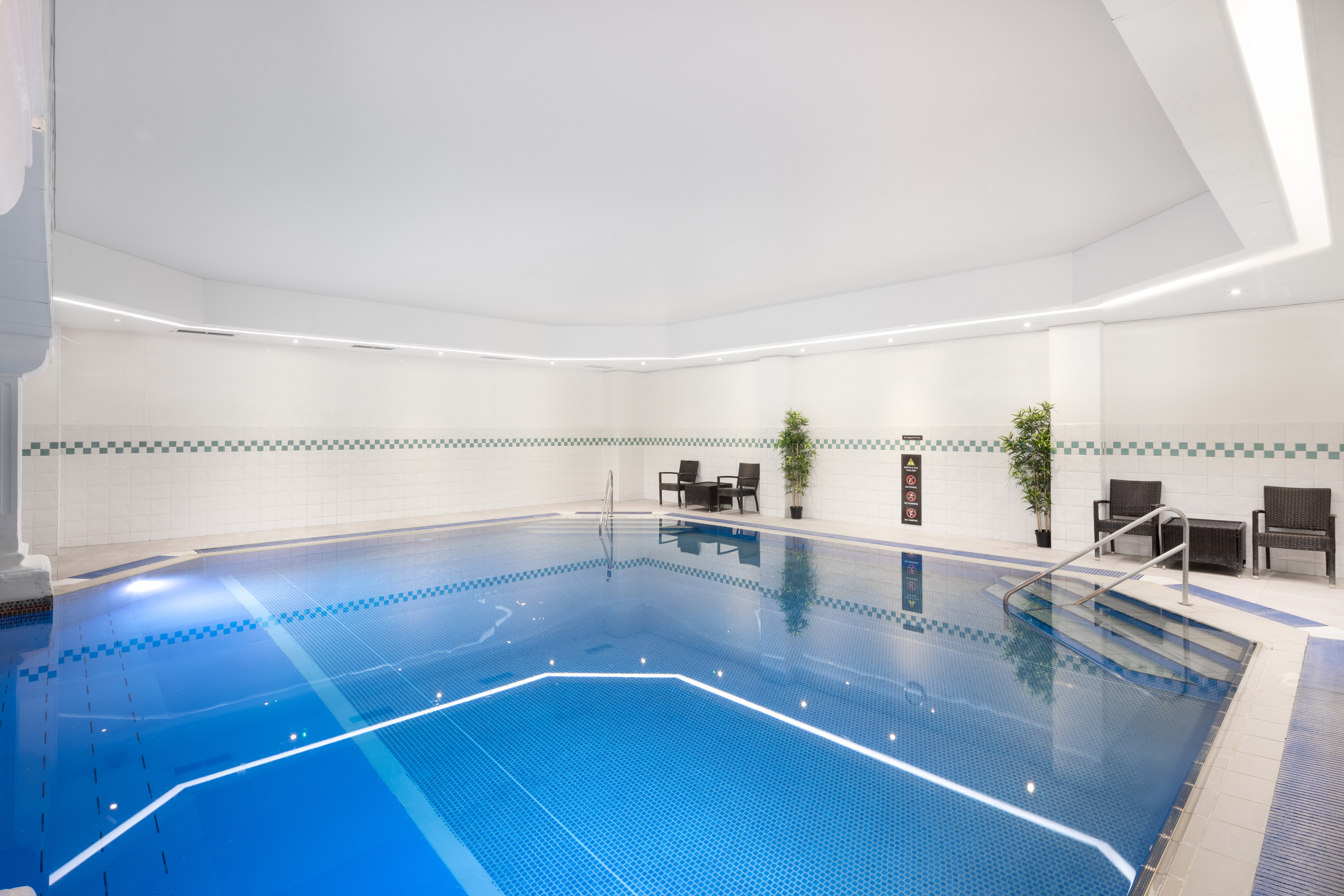 indoor pool with chairs and plants
