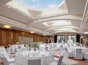 Place Settings and Flowers on Round Dining Tables With White Linens in Hilton Ballroom With Sky Lights