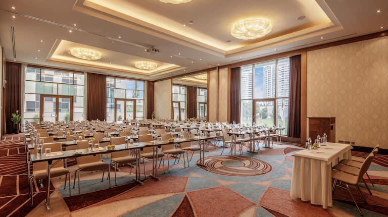 Sala de conferință Waldorf pregătită pentru cursuri, cu mese și scaune așezate cu fața spre podium și masa conferențiarului