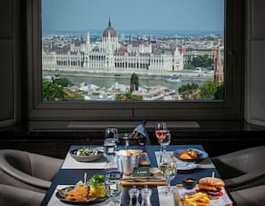 Ein zum Abendessen gedeckter Tisch in einem Restaurant mit großen Fenstern und Blick auf die Donau