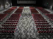 Large auditorium with stage, red chairs and grey patterned flooring