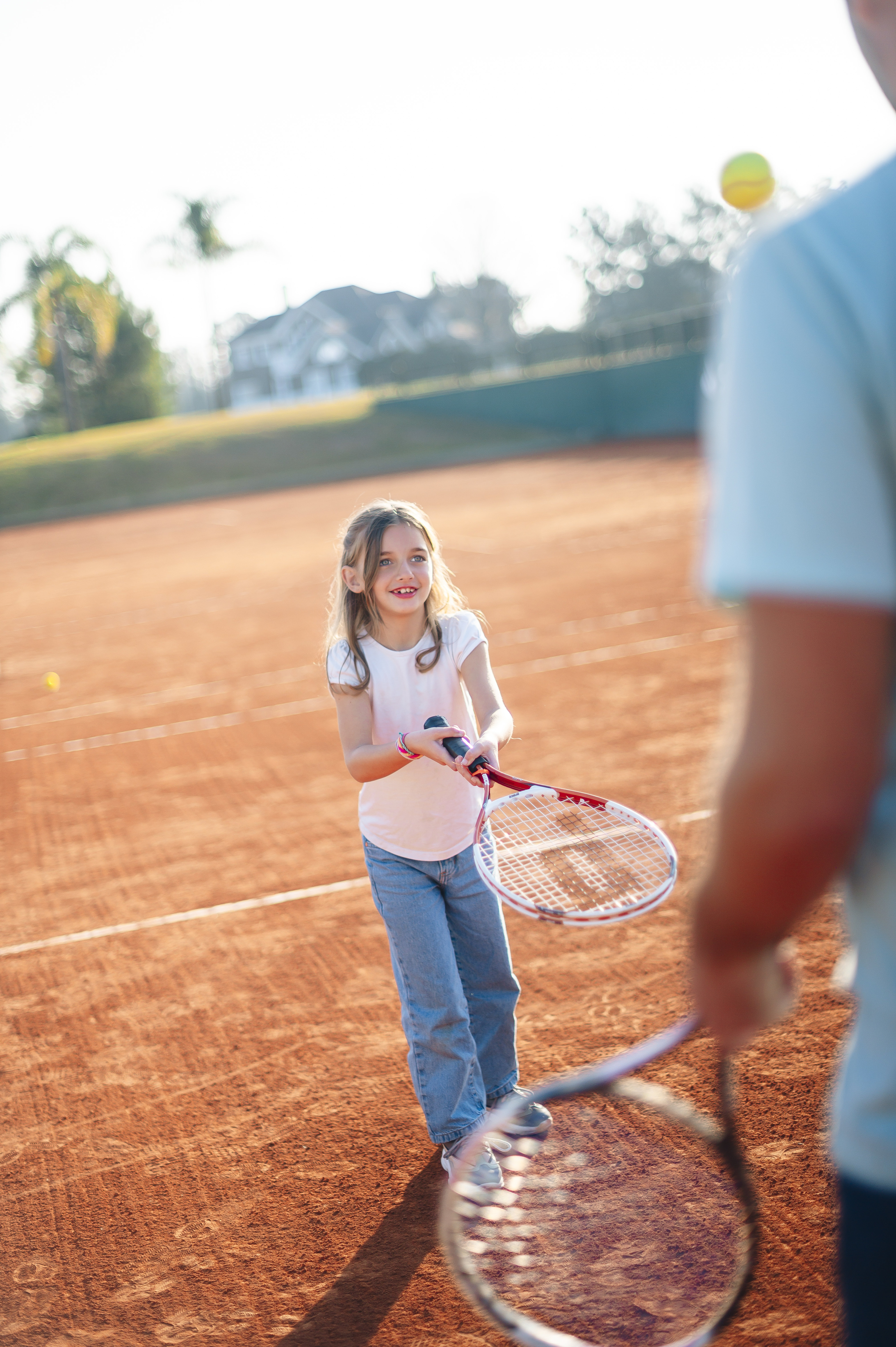 una niña jugando al tenis con un adulto