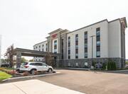 Daytime View of Hotel Exterior, Signage, Flagpole, Landscaping, Circle Drive, and Parking Lot with Guest Cars