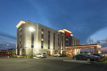 Illuminated Hotel Exterior, Signage, Circle Drive, and Guest Cars on Parking Lot at Dusk