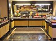 Hot and Cold Buffet and Beverage Selections in Breakfast Area With Plates, Utensils, and Condiments 