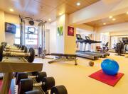 Fitness Center With Free Weights, TV, Weight Machine, Bench, Cardio Equipment, Blue Exercise Ball, and Mirrored Wall