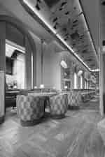 Hotel restaurant with round tables, patterned chairs, arched windows, and hanging lamps