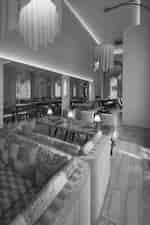 Hotel dining room with long tables, upholstered seating, mirrors, and hanging pendant lights