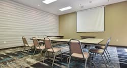 Meeting room with long table and multiple chairs and projector screen.