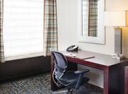 Detailed View of Window With Open Drapes, Mirror Above Work Desk With Phone and Illuminated Lamp,, and Ergonomic Chair