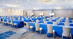 Classroom Setup For Corporate Event in Meeting Room With Tables and Chairs Facing Three TVs