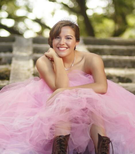 Happy Teen Girl Sitting on Stairs Wearing Pink Quinceañera Dress