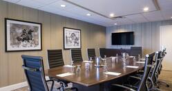 Wall Art, TV, and Seating for 10 at Large Table With Water Pitchers and Glasses in Boardroom