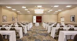 Classroom Setup in Ballroom With Wall Art, Tables and Chairs Facing Projector Table and Presentation Screen