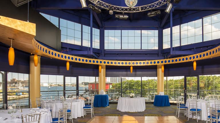Spacious Ballroom Dining Area with Roundtables, Chairs and Harbor View