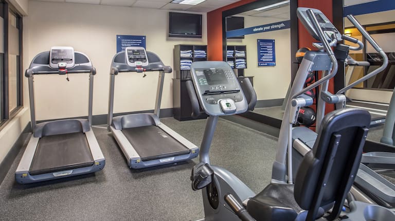 Fitness Center With Cardio Equipment, TV, Towel Station, Weight Balls, and Large Mirrors