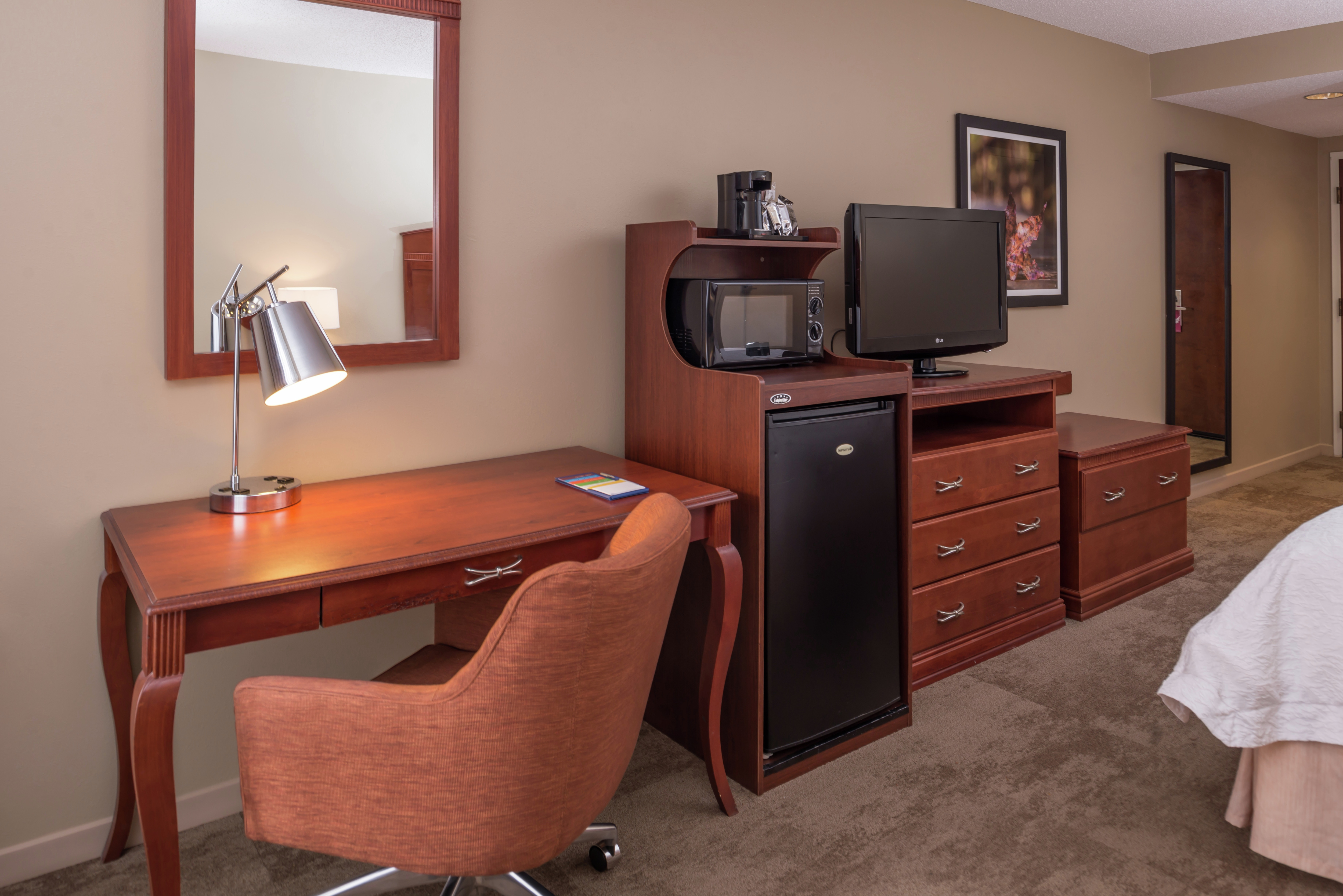 King Bed, Work Desk, Hospitality Center With Microwave and Mini Fridge, TV, and Full Length Mirror in Guest Room