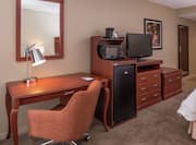 King Bed, Work Desk, Hospitality Center With Microwave and Mini Fridge, TV, and Full Length Mirror in Guest Room