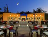 Outdoor social space with dining tables and chairs, Egyptian themed, lit up at dusk
