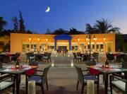 Outdoor social space with dining tables and chairs, Egyptian themed, lit up at dusk