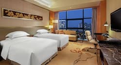Executive Twin Beds Room with City View a Desk a Sofa and HDTV