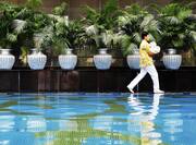 Man Walking with Towels Around Indoor Swimming Pool