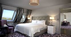 Suite bedroom with king bed, stting area and angled windows over bed