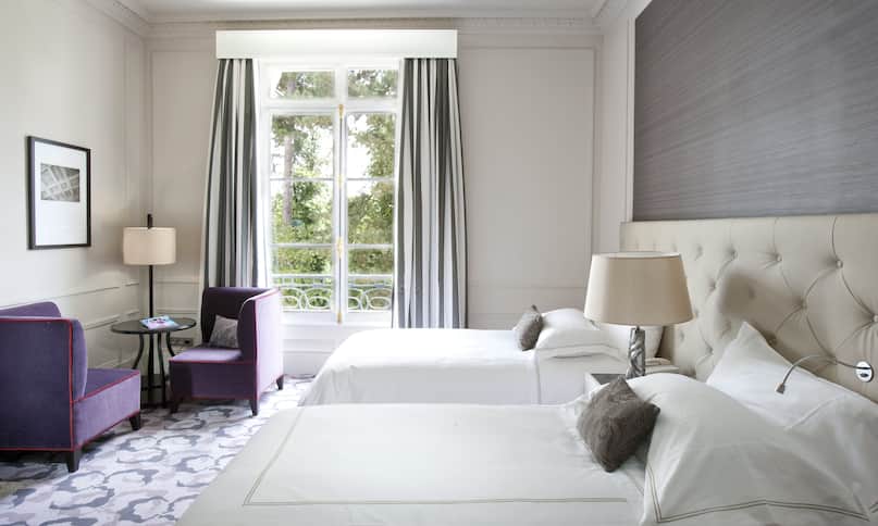 Zwei Betten im Hotelzimmer mit Sitzbereich und Gartenblick – nächste Umstellung