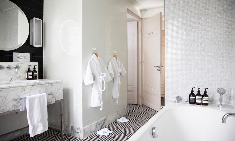 Badezimmer der Familiensuite mit Badewanne, weißen Bademänteln und Schlafcouchen – früherer Übergang