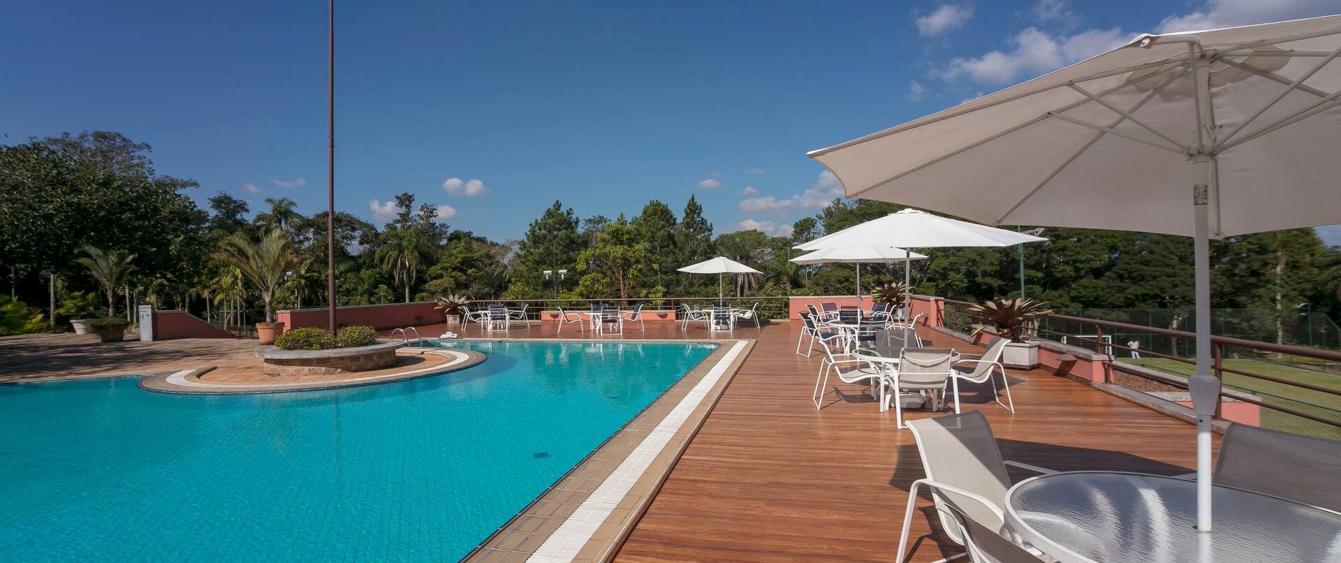 Outdoor Pool Area with Tables and Chairs under Umbrellas