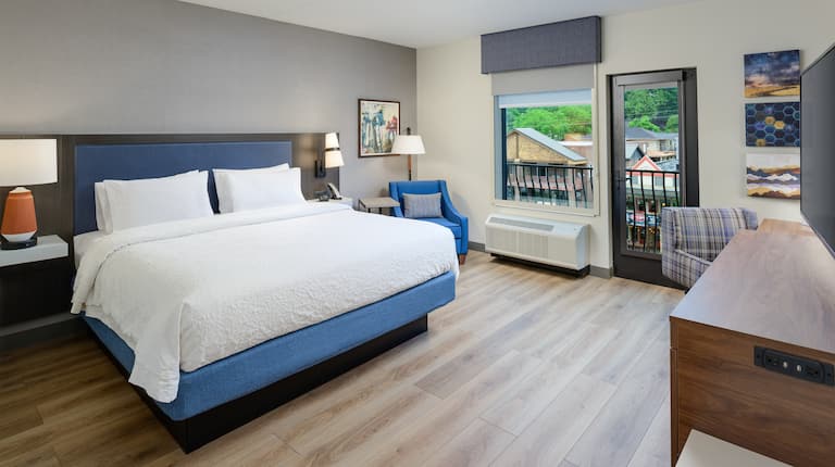 Kind Guest Room with Armchair Balcony HDTV and Desk Area