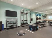 Convenient on-site fitness center featuring free weights, TV, benches, and mirrored walls.