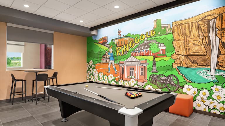 Fun on-site play area for guests to enjoy and relax featuring ample seating, pool table, and colourful mural.