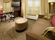 Guest Suite Lounge Area with Sofa, Footrest, Work Desk and Wall Mounted TV