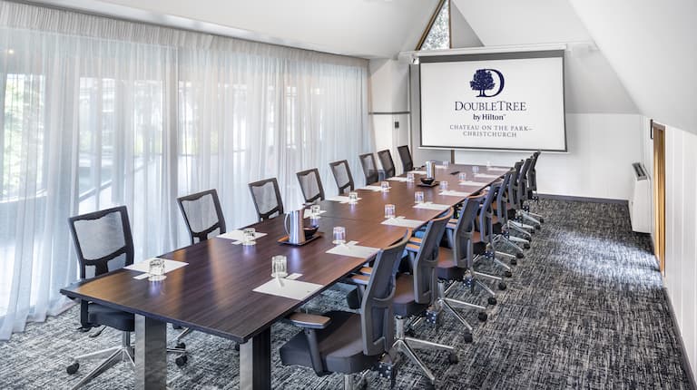 a boardroom table and a presentation screen in a meeting room