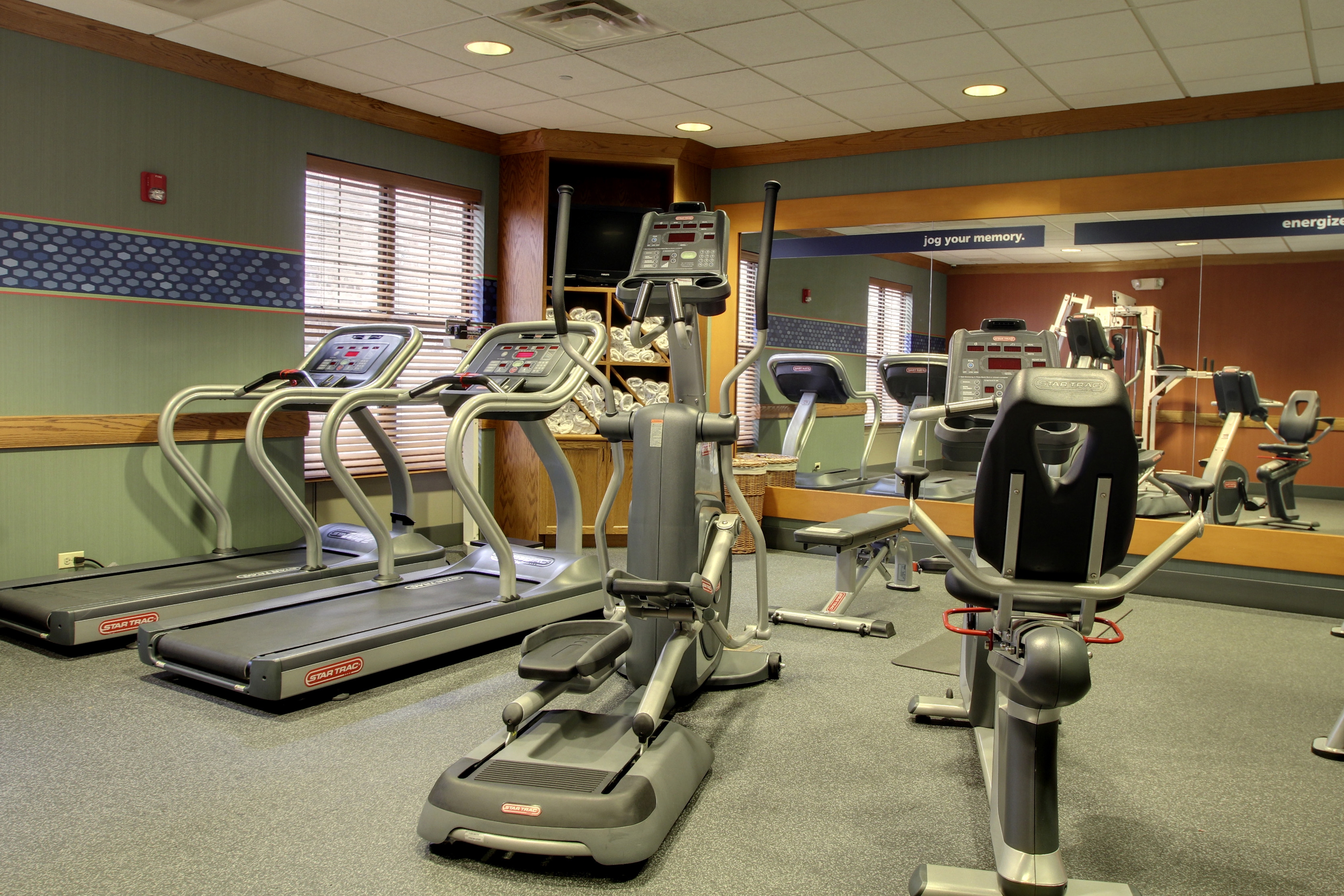 Fitness Center With Cardio Equipment Facing Mirrored Wall