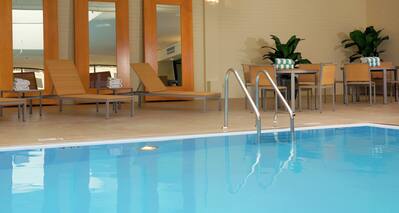 Tables, Chairs, Three Full Length Mirrors, and Relaxation Loungers by Indoor Pool