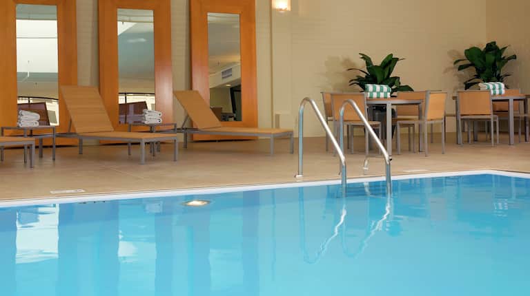 Tables, Chairs, Three Full Length Mirrors, and Relaxation Loungers by Indoor Pool