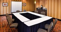 Meeting Room with O-Shape Table Setup with Chairs, Projector Screen and Coffee Station